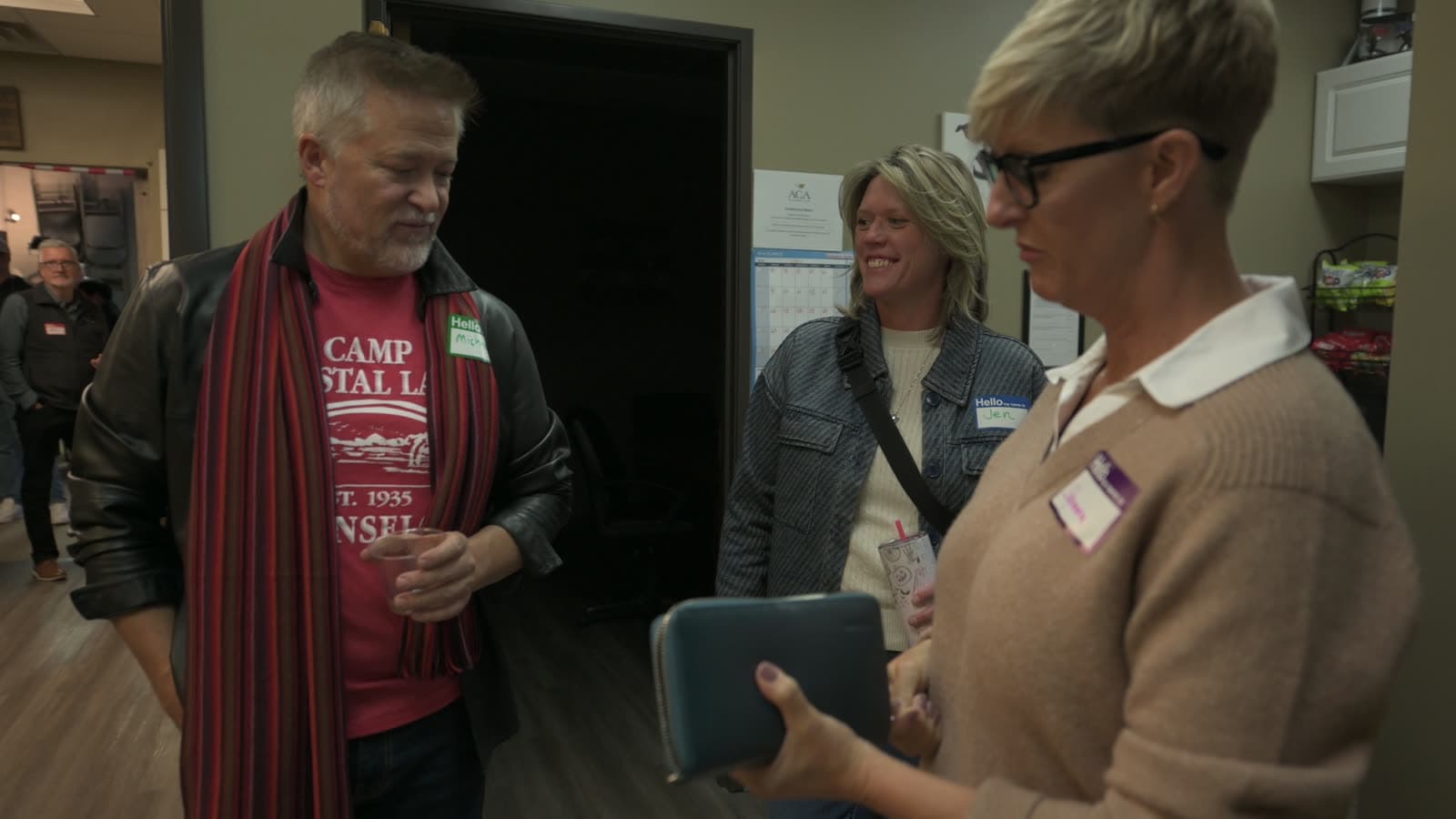 Three attendees in conversation near the entrance